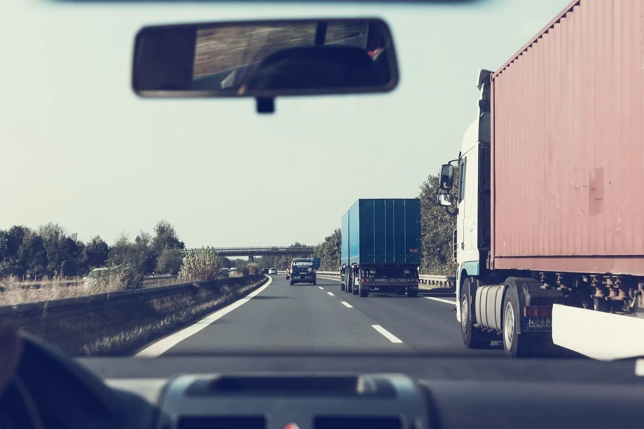 18 wheelers seen on a road from the dashboard.
