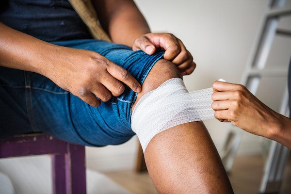 man having his knee wrapped in gauze possibly after an injury.
