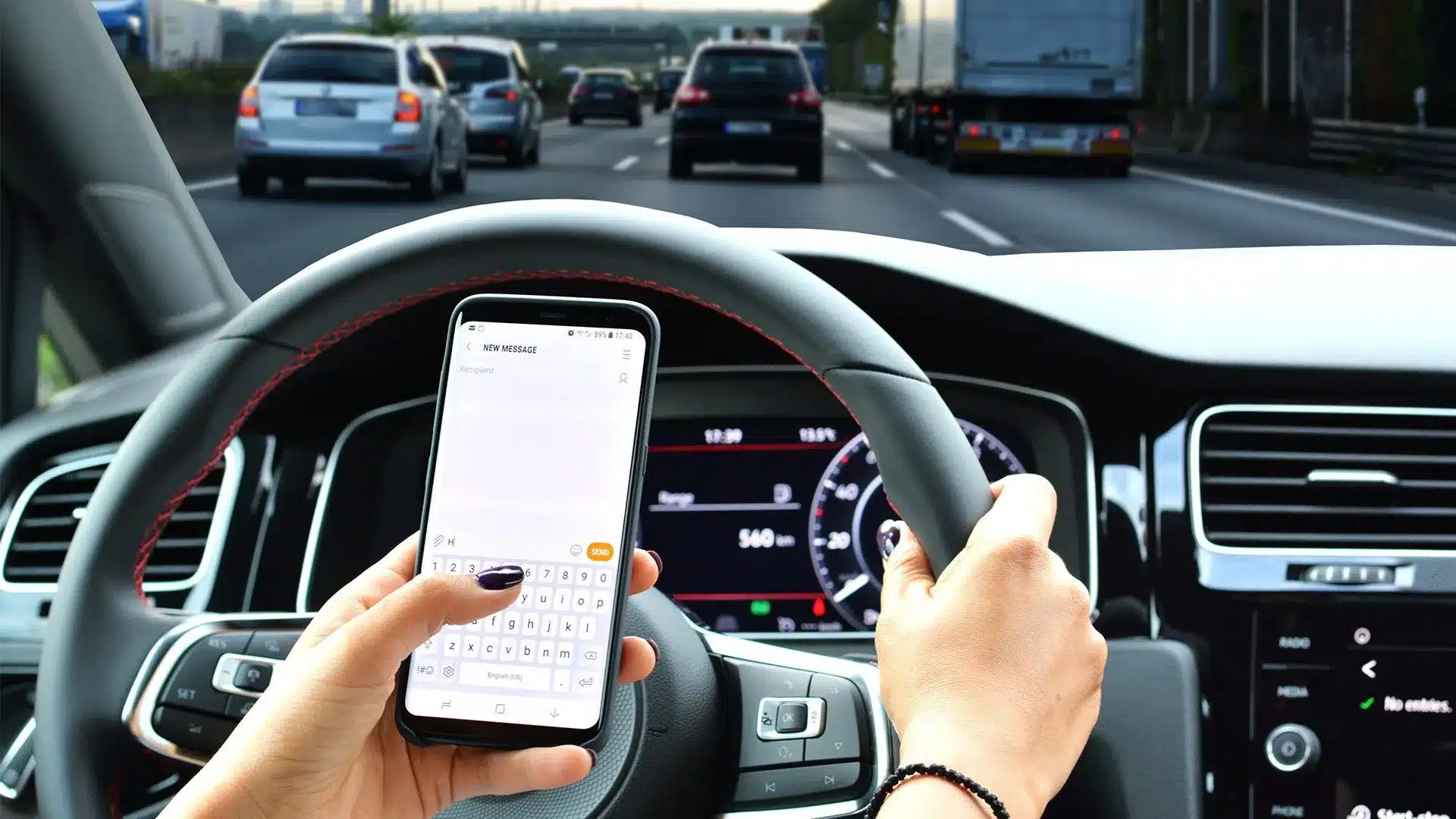 Woman looking at her phone to text while in traffic on the highway.