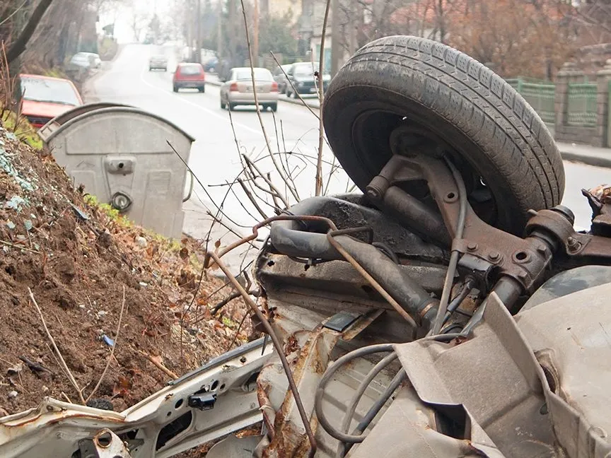 A truck laying upside down on the side of a highway.