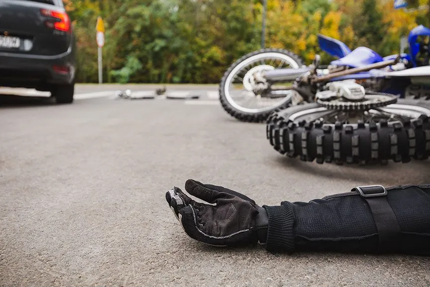 Motorcycle rider on the ground after being involved in an accident with a car.