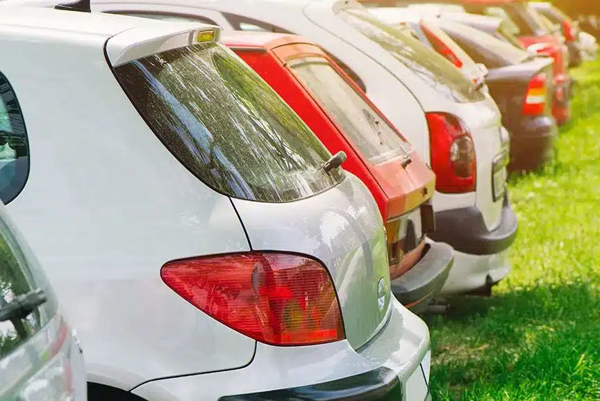 A row of cars parked on grass.