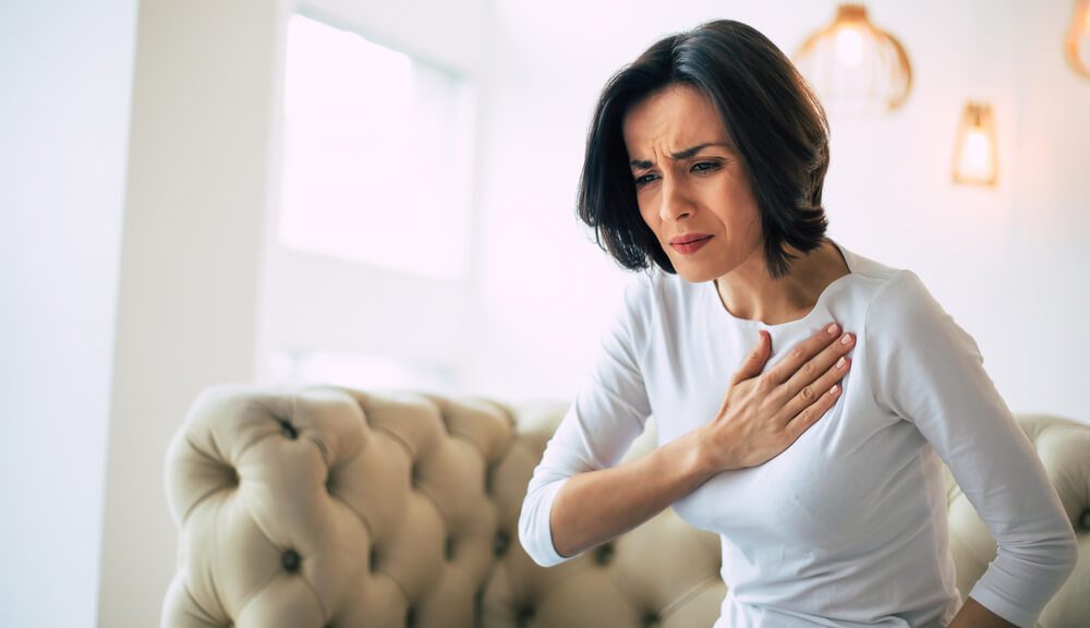 Pressure in the chest. Close-up photo of a stressed woman who is suffering from a chest pain