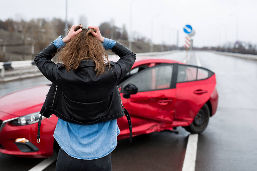 Woman stands near a broken car after an accident. call for help.