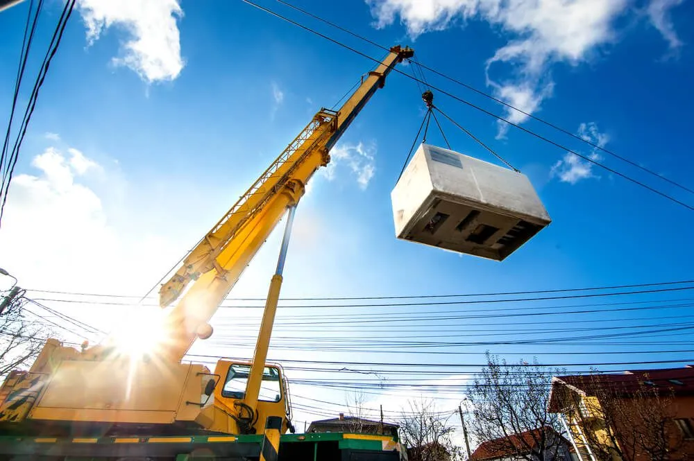 Mobile crane that works by lifting and moving a heavy electric generator.