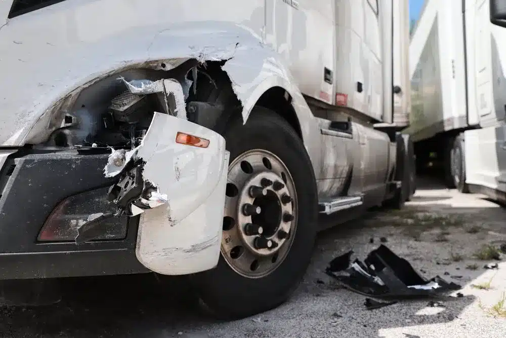 A white semi-truck with front-end damage.