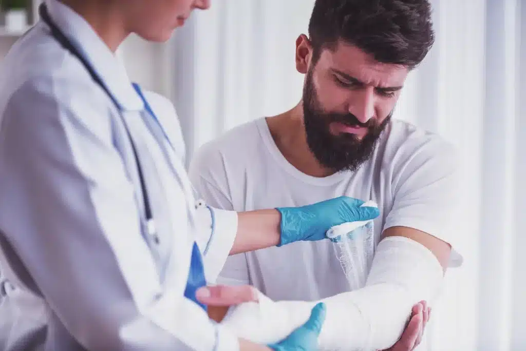 A doctor wrapping an injured man's arm.