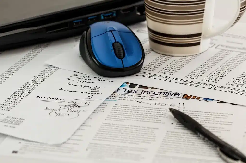 A computer mouse, receipts and documents on a desk.