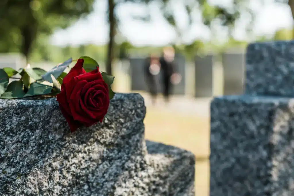 A rose flower resting on top of a grave.