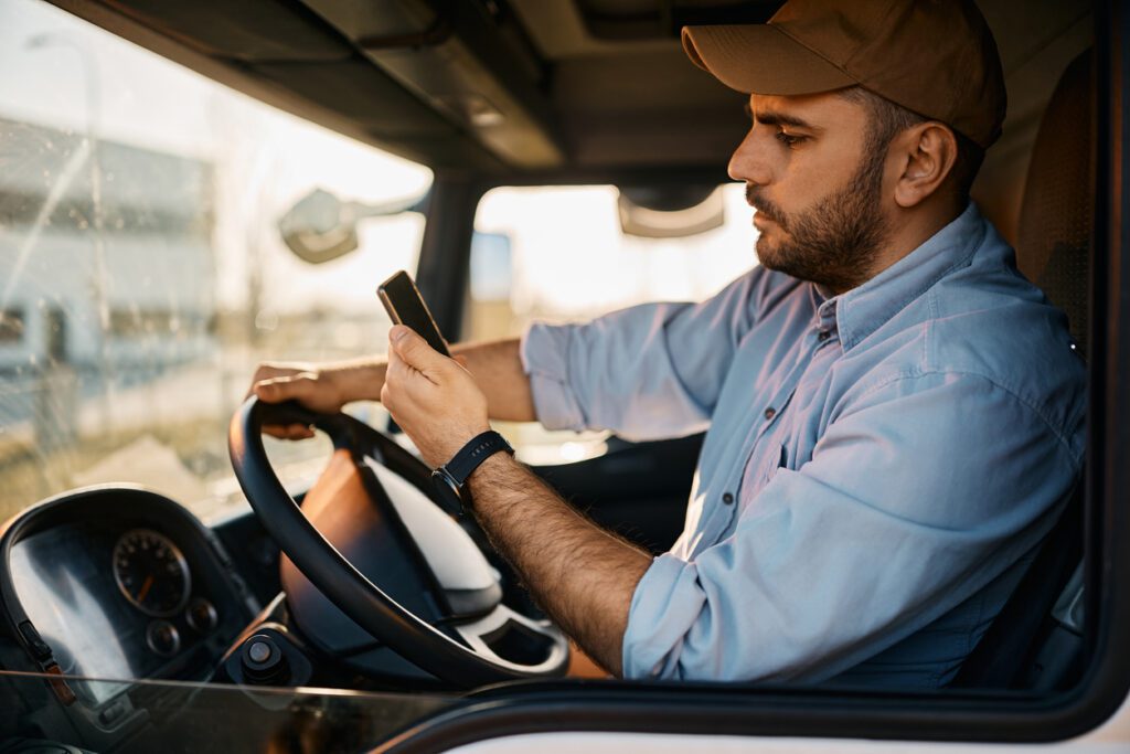 A truck driver looking at his phone while driving.