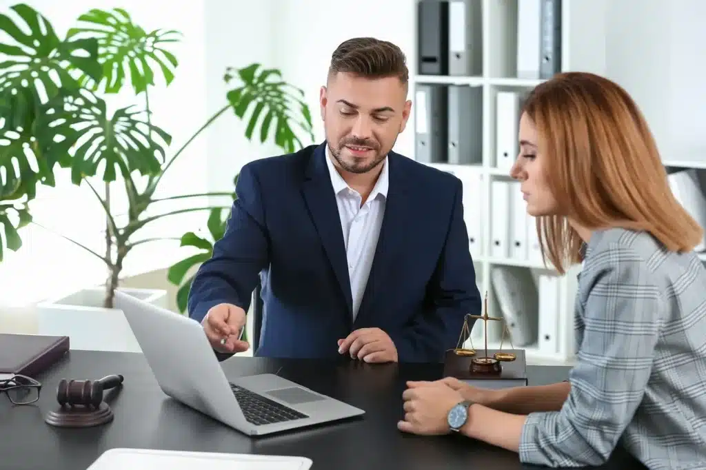 An attorney speaking with a client and interacting with a laptop computer.