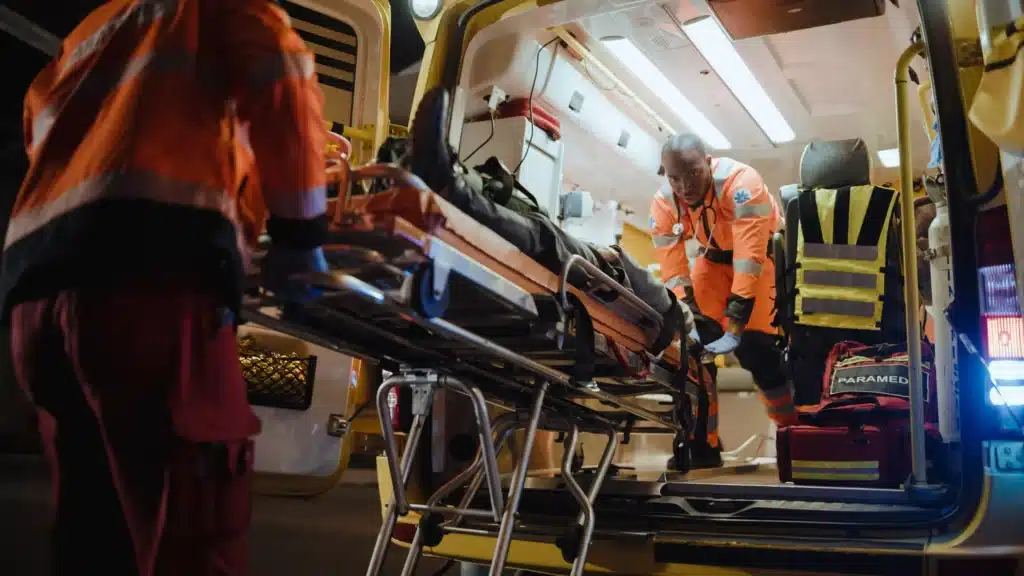 Two emergency medical technicians rushing out of the back of an ambulance.